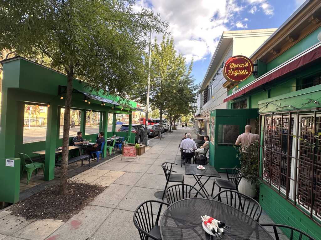 The real green Queen's English facade and sidewalk seating on 11th Street NW