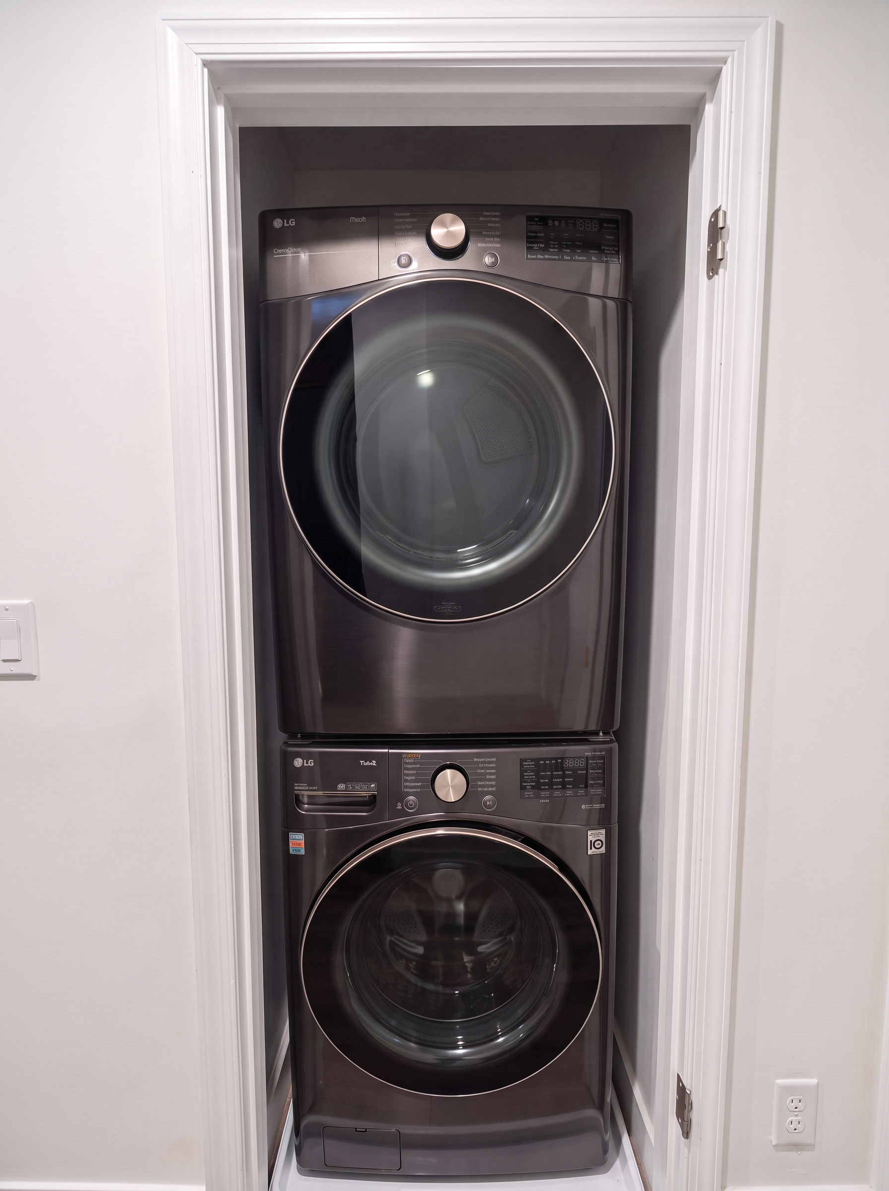 Graphite LG smart washer and dryer stacked in the upstairs en-suite laundry closet